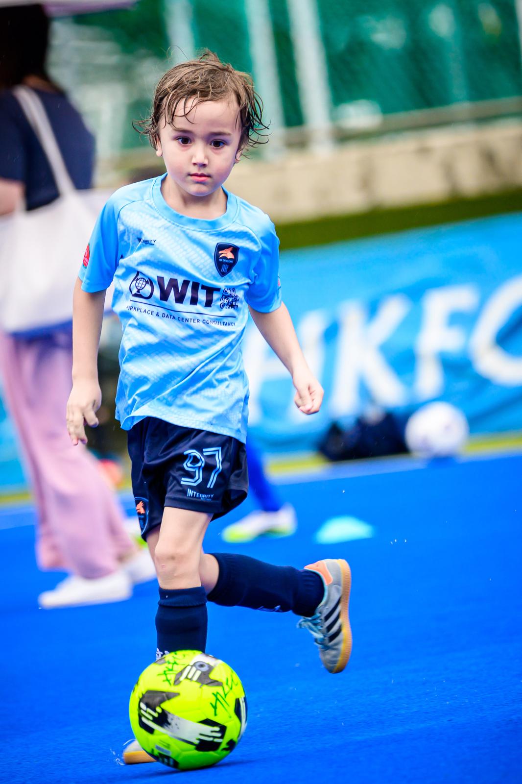 A young Dragon running with the ball on an artificial pitch