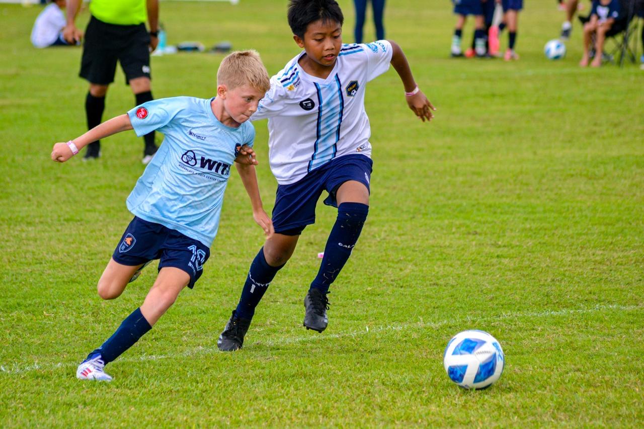 Two young players battling for the ball on the grass