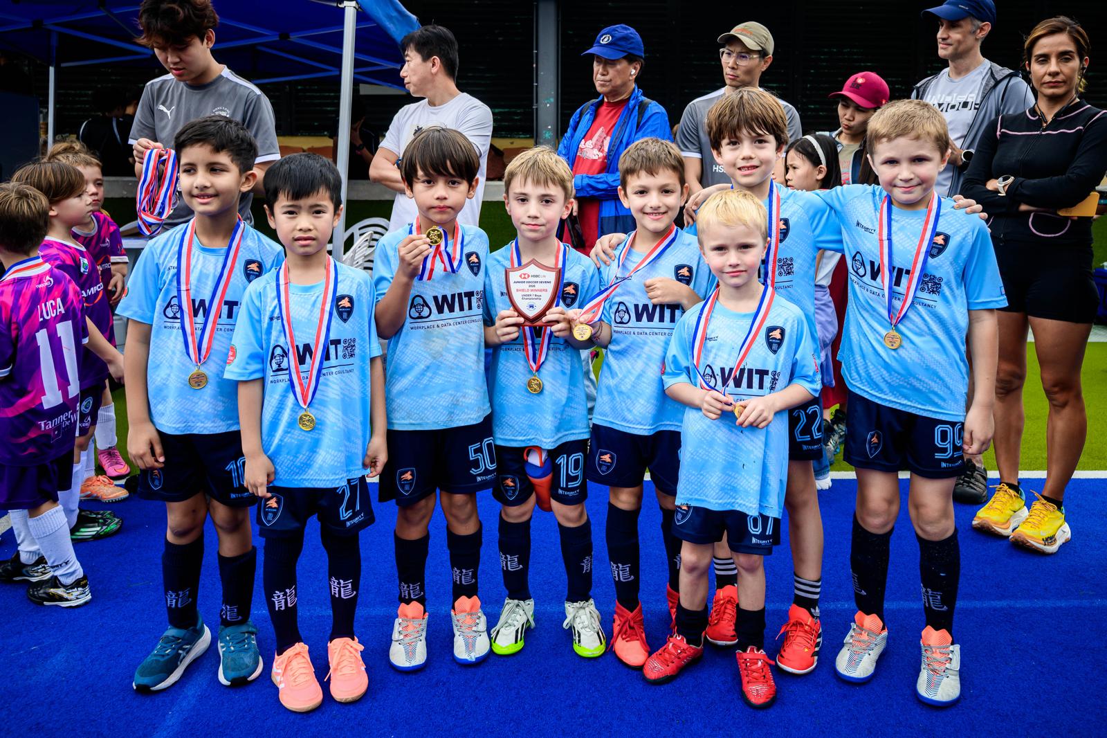 A Dragons squad posing with medals on an artificial pitch
